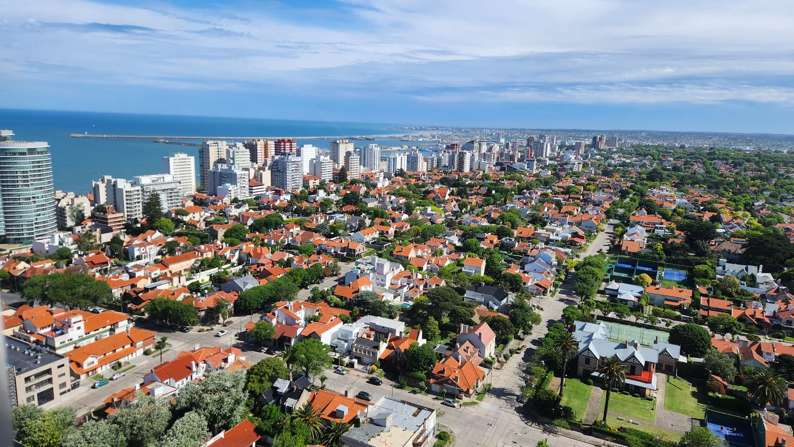 Vista aérea de los techos de tejas de Los Troncos con Playa Grande y el puerto al fondo
